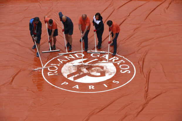 FILE PHOTO: Tennis - French Open - Roland Garros, Paris, France - June 4, 2021 Ground staff clear water of a cover after rain stops play 