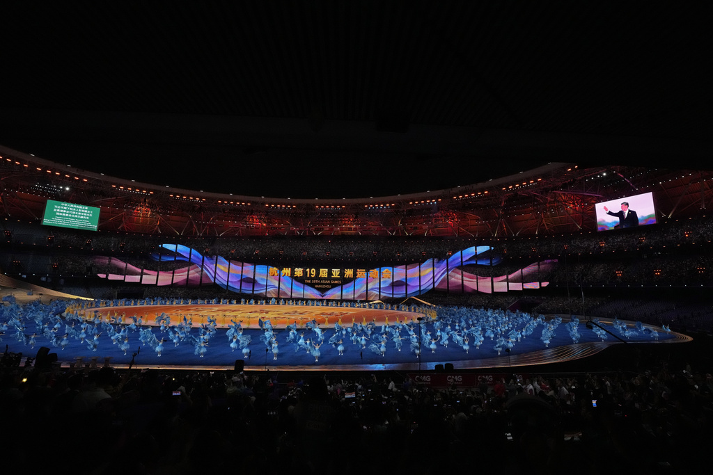 Artists perform as live pictures of Chinese President Xi Jinping waving the spectators are displayed on a large screen during the during the opening ceremony of the 19th Asian Games in Hangzhou, China,