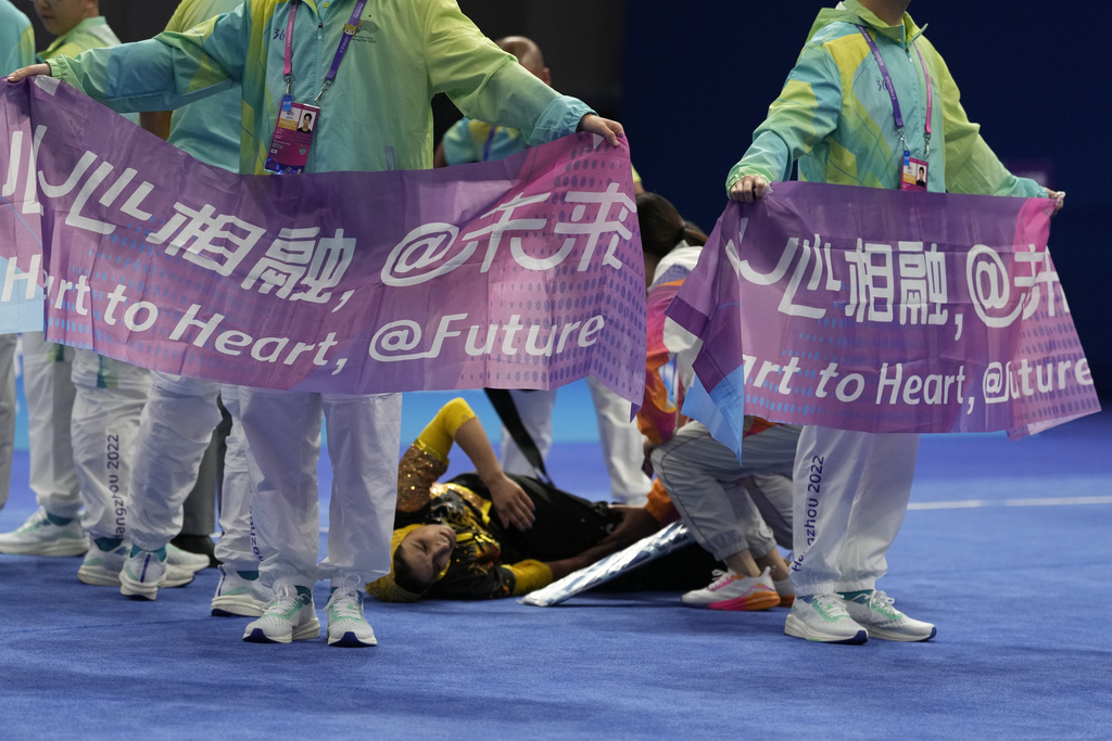 Volunteers hold up banners with the slogan "Heart to Heart" to block the view as medics attend to Iran's Mina Panahi Dorcheh who injured her leg in the Wushu Women's Nanquan competition for the 19th Asian Games in Hangzhou, China, Tuesday, Sept. 26, 2023.