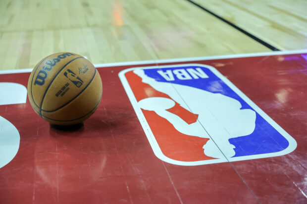 A basketball is placed on the court next to an NBA logo during a break in the first half of a 2023 NBA Summer League game 