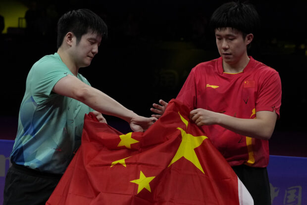 China's Wang Chuqin, right keeps a Chinese national flag with his compatriot Fan Zhendong after their Table Tennis Men's Singles Final match for the 19th Asian Games in Hangzhou, Monday, Oct. 2, 2023