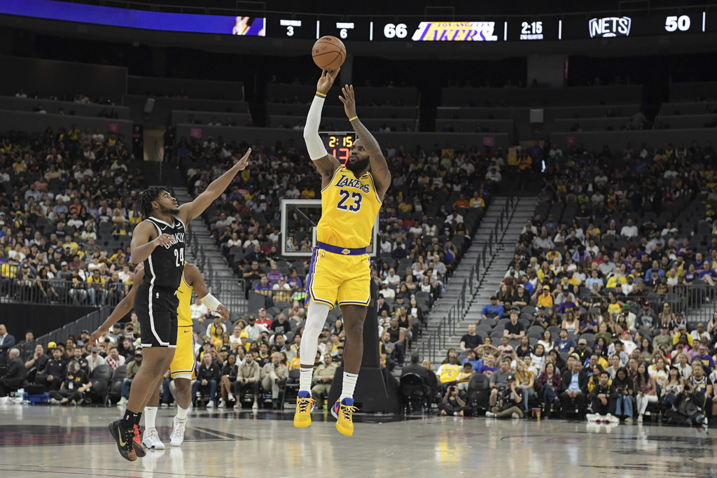 Los Angeles Lakers forward LeBron James (23) shoots a 3-pointer over Brooklyn Nets guard Cam Thomas (24) during the first half of a preseason NBA basketball game, Monday, Oct. 9, 2023, in Las Vegas.