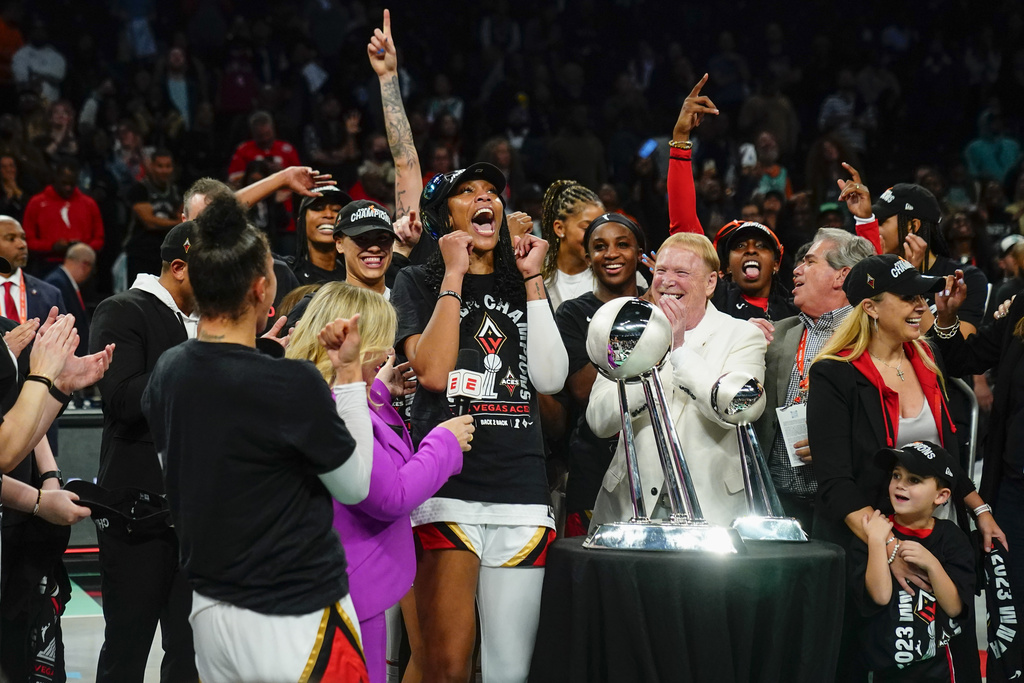 Las Vegas Aces' A'ja Wilson and Mark Davis celebrate with teammates next to the trophy after Game 4 of a WNBA basketball final playoff series against the New York Liberty Wednesday, Oct. 18, 2023, in New York. The Aces won 70-69.