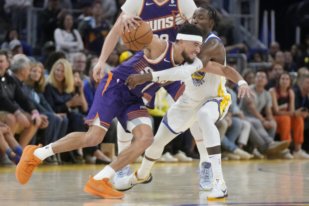 Phoenix Suns guard Devin Booker, left, drives to the basket against Golden State Warriors forward Jonathan Kuminga during the second half of an NBA basketball game in San Francisco, Tuesday, Oct. 24, 2023. 