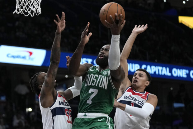 Boston Celtics guard Jaylen Brown (7) shoots over Washington Wizards guard Delon Wright, left, and guard Johnny Davis, right, during the second half of an NBA basketball game Monday, Oct. 30, 2023, in Washington