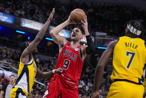 Chicago Bulls center Nikola Vucevic (9) shoots between Indiana Pacers forward Aaron Nesmith (23) and guard Buddy Hield (7) during the second half of an NBA 