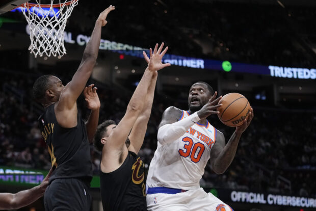 New York Knicks forward Julius Randle (30) goes to the basket as Cleveland Cavaliers forward Evan Mobley, left, and forward Georges Niang, center, defend during the second half of an NBA basketball game Tuesday, Oct. 31, 2023, in Cleveland
