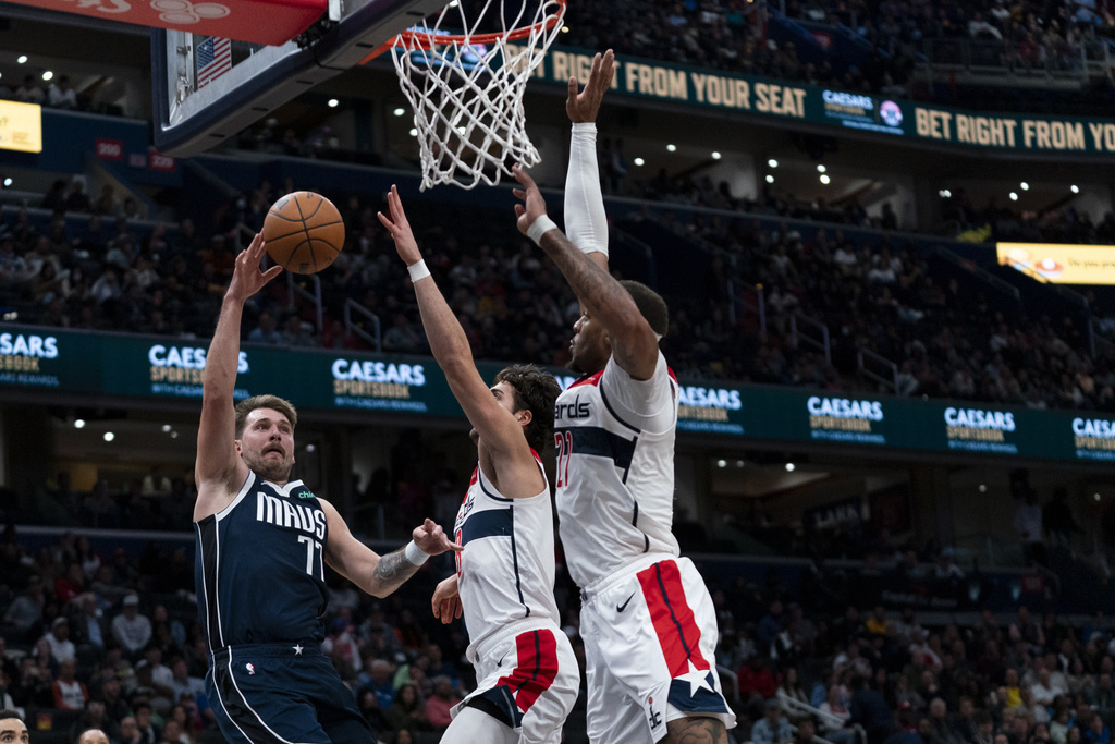 Dallas Mavericks guard Luka Doncic (77) shoots against Washington Wizards forward Deni Avdija (8) and Wizards center Daniel Gafford (21) during the second half of an NBA basketball game, Wednesday, Nov. 15, 2023, in Washington.