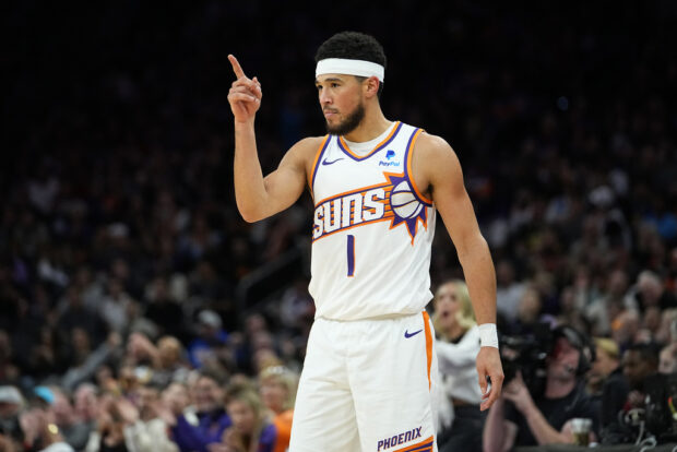 Phoenix Suns guard Devin Booker (1) points after a basket against the Golden State Warriors during the second half of an NBA basketball game, Wednesday, Nov. 22, 2023, in Phoenix. 