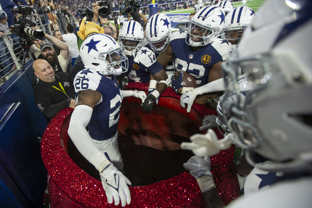 Dallas Cowboys cornerback DaRon Bland (26) celebrates in the Salvation Army Red Kettle with teammates after running back an interception for a touchdown during an NFL football game against the Washington Commanders, Thursday, Nov. 23, 2023, in Arlington, Texas.