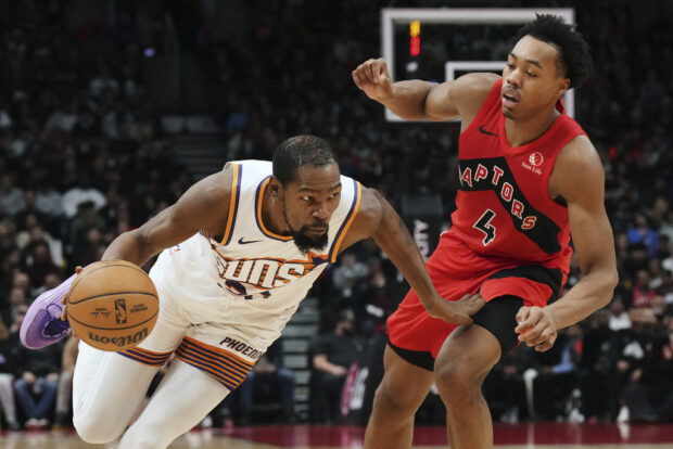 Phoenix Suns' Kevin Durant (35) drives past Toronto Raptors' Scottie Barnes (4) during the second half of an NBA basketball game in Toronto on Wednesday, Nov. 29, 2023. (