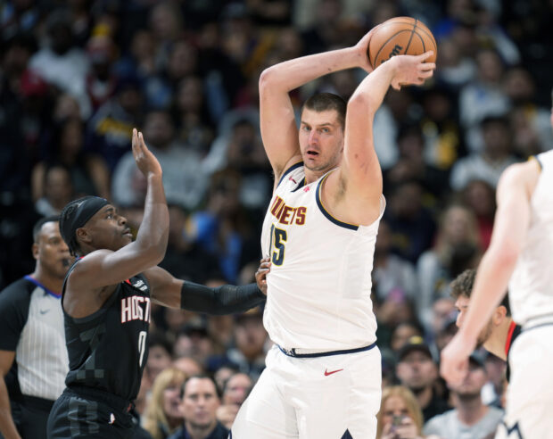 Denver Nuggets center Nikola Jokic, right, pulls in a rebound as Houston Rockets guard Aaron Holiday defends in the second half of an NBA basketball game on Wednesday, Nov. 29, 2023, in Denver.