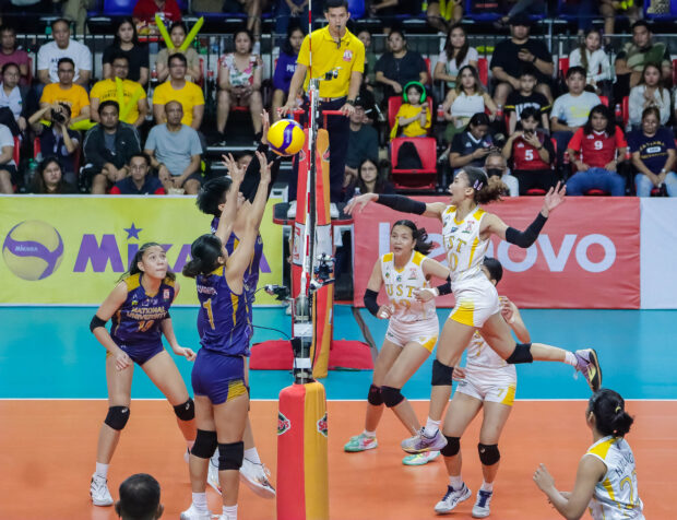 UST Growling Tigers' Xyza Gula soars for a hit against NU defenders. –
