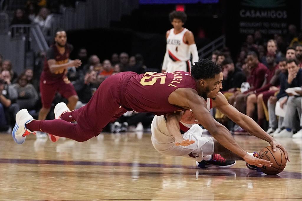 Cleveland Cavaliers guard Donovan Mitchell (45) and Portland Trail Blazers guard Malcolm Brogdon reach for the ball during the second half of an NBA basketball game Thursday, Nov. 30, 2023, in Cleveland.
