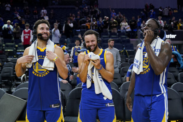 Golden State Warriors guards Klay Thompson, left, and Stephen Curry and forward Draymond Green, right, laugh while being interviewed after the team's victory over the Los Angeles Clippers in an NBA basketball game Thursday, Nov. 30, 2023, in San Francisco. 