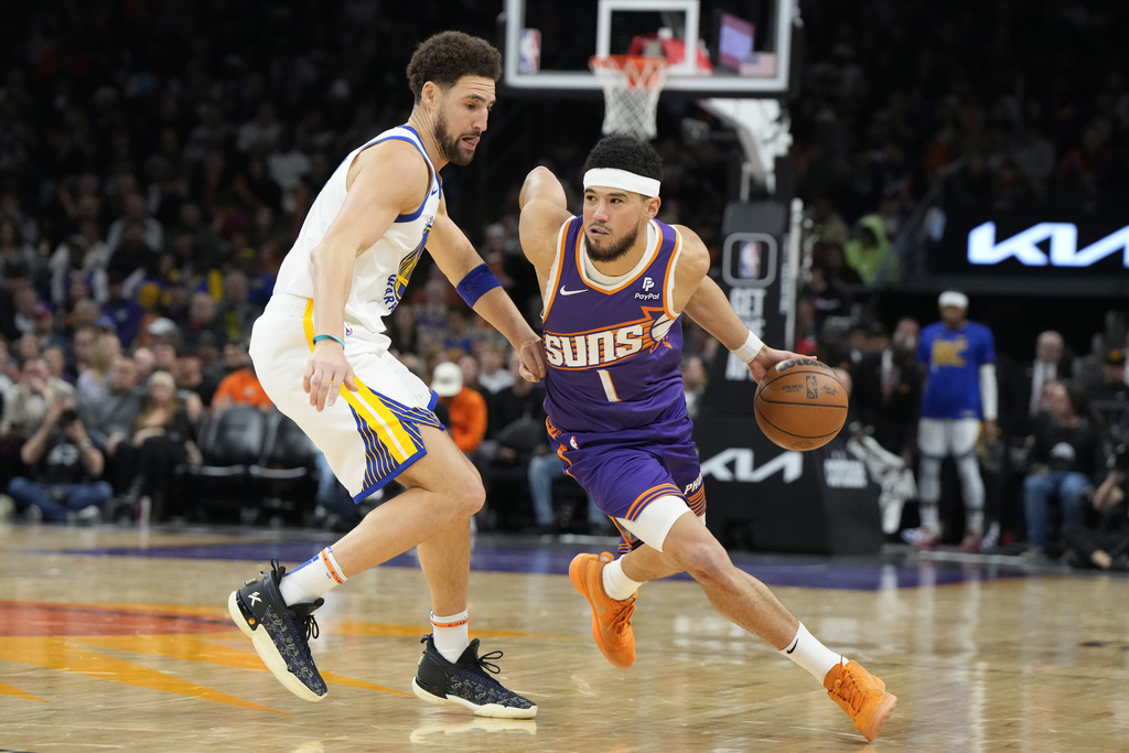 Phoenix Suns guard Devin Booker (1) drives against Golden State Warriors guard Klay Thompson during the second half of an NBA basketball game, Tuesday, Dec. 12, 2023, in Phoenix.