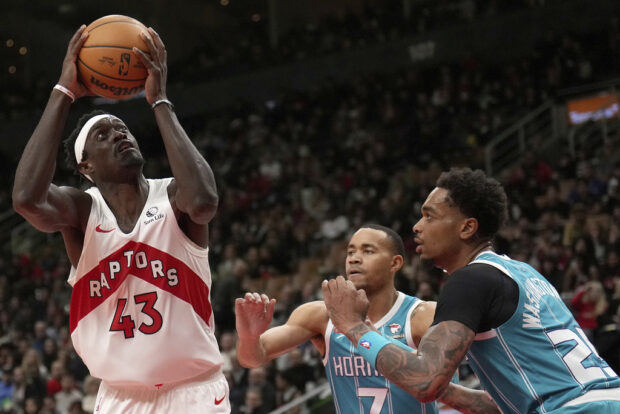Toronto Raptors forward Pascal Siakam (43) eyes the basket under pressure from Charlotte Hornets guard Bryce McGowens (7) and teammate P.J. Washington (25) during the second half of an NBA basketball game in Toronto, Monday, Dec. 18, 2023. 