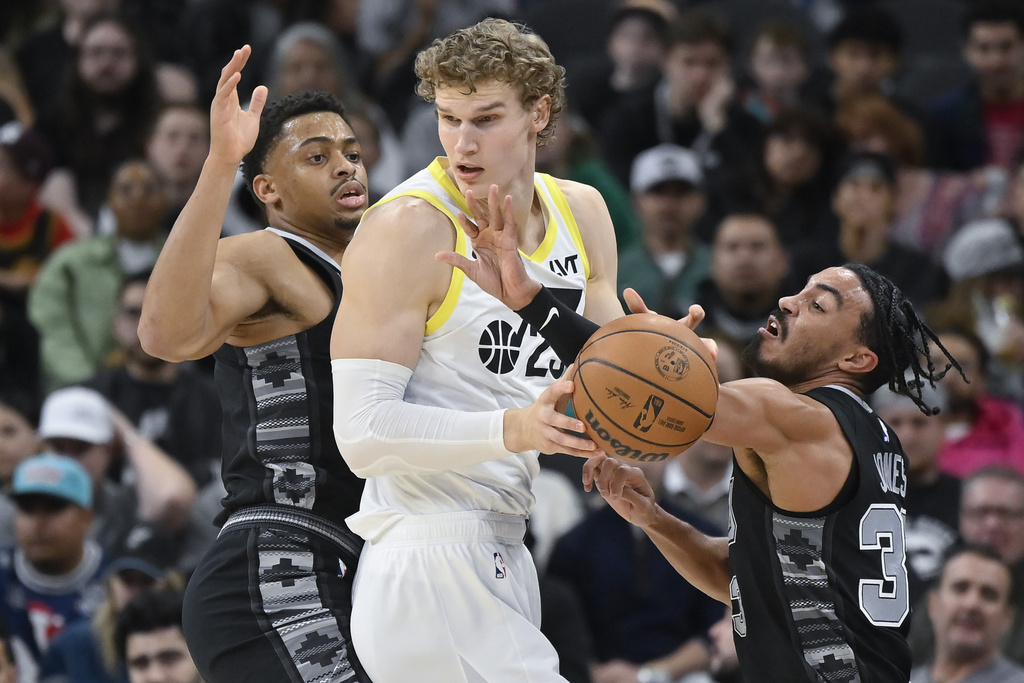 Utah Jazz's Lauri Markkanen, center, is defended by San Antonio Spurs' Tre Jones, right, and Keldon Johnson during the first half of an NBA basketball game Tuesday, Dec. 26, 2023, in San Antonio. 