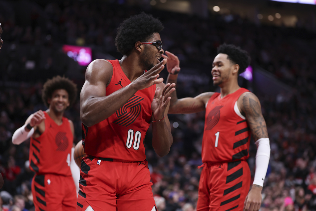 Portland Trail Blazers guard Matisse Thybulle, left, guard Scoot Henderson, middle, and guard Anfernee Simons celebrate after the Sacramento Kings were called for a foul during the first half of an NBA basketball game Tuesday, Dec. 26, 2023, in Portland, Oregon. 