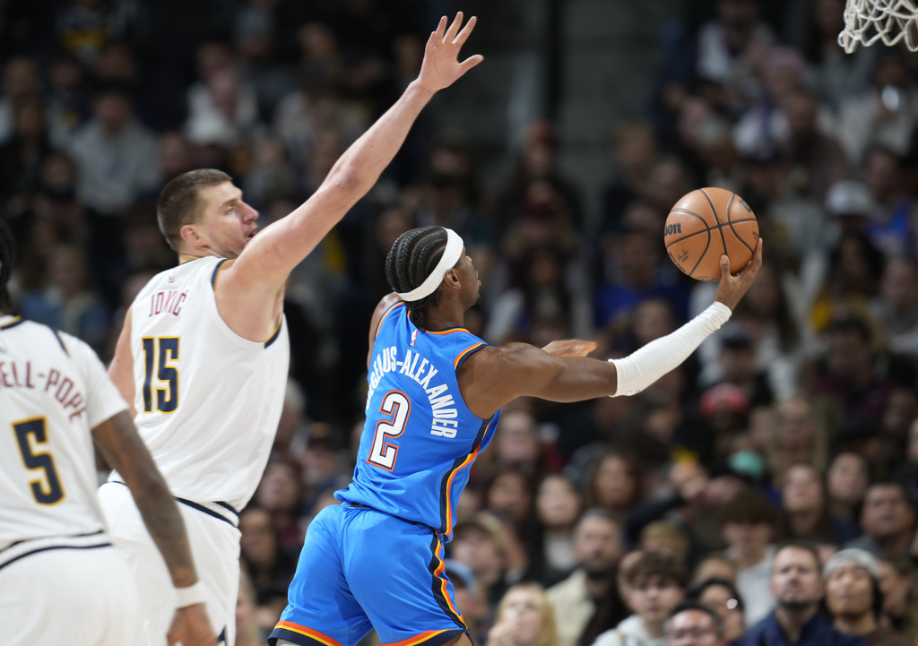 Oklahoma City Thunder guard Shai Gilgeous-Alexander, right, gets past Denver Nuggets center Nikola Jokic (15) to the basket in the first half of an NBA basketball game Friday, Dec. 29, 2023, in Denver. 