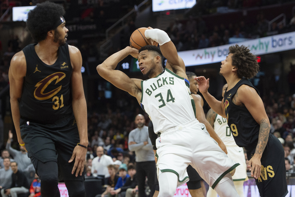 Giannis Antetokounmpo (34) of the Milwaukee Bucks looks to pass between Jarrett Allen (31) of the Cleveland Cavaliers and Craig Porter (9) during the second half of an NBA basketball game in Cleveland, Friday, Dec. 29, 2023 . 