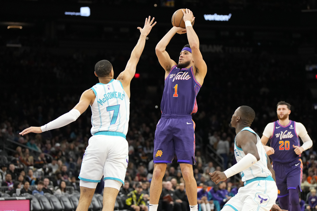 Phoenix Suns guard Devin Booker (1) shoots over Charlotte Hornets guard Bryce McGowens (7) during the second half of an NBA basketball game, Friday, Dec. 29 2023, in Phoenix. 