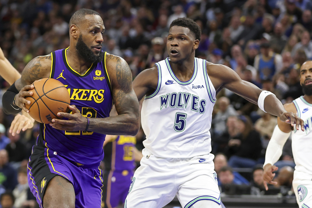 Los Angeles Lakers forward LeBron James, left, drives against Minnesota Timberwolves guard Anthony Edwards (5) during the second half of an NBA basketball game Saturday, Dec. 30, 2023, in Minneapolis.