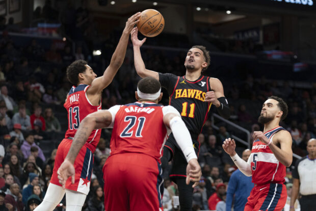 Atlanta Hawks' Trae Young (11) fight for the ball with Washington Wizards' Jordan Poole (13) during the second half of an NBA basketball game Sunday, Dec. 31, 2023, in Washington. 