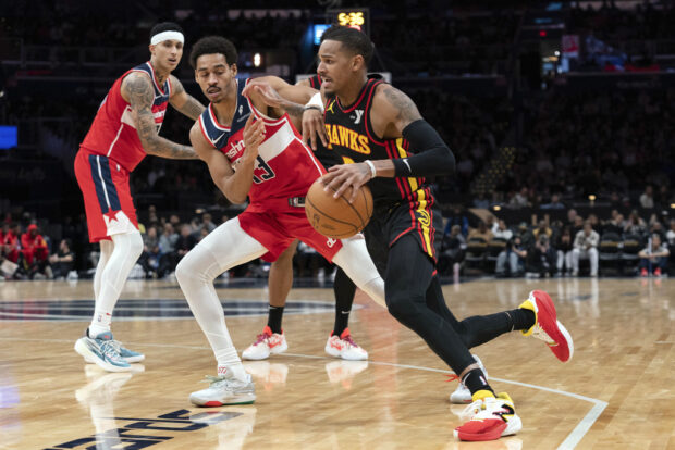 Atlanta Hawks' Dejounte Murray, right, fights for the ball with Washington Wizards' Jordan Poole (13) during the second half of an NBA basketball game Sunday, Dec. 31, 2023, in Washington