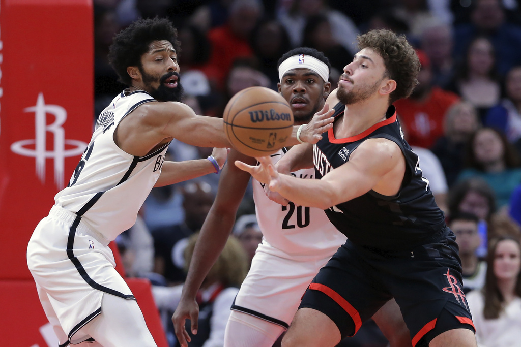Houston Rockets center Alperen Sengun, right, passes the ball under pressure from Brooklyn Nets guard Spencer Dinwiddie, left, and center Day'Ron Sharpe, center, during the second half of an NBA basketball game Wednesday, Jan. 3, 2024, in Houston.