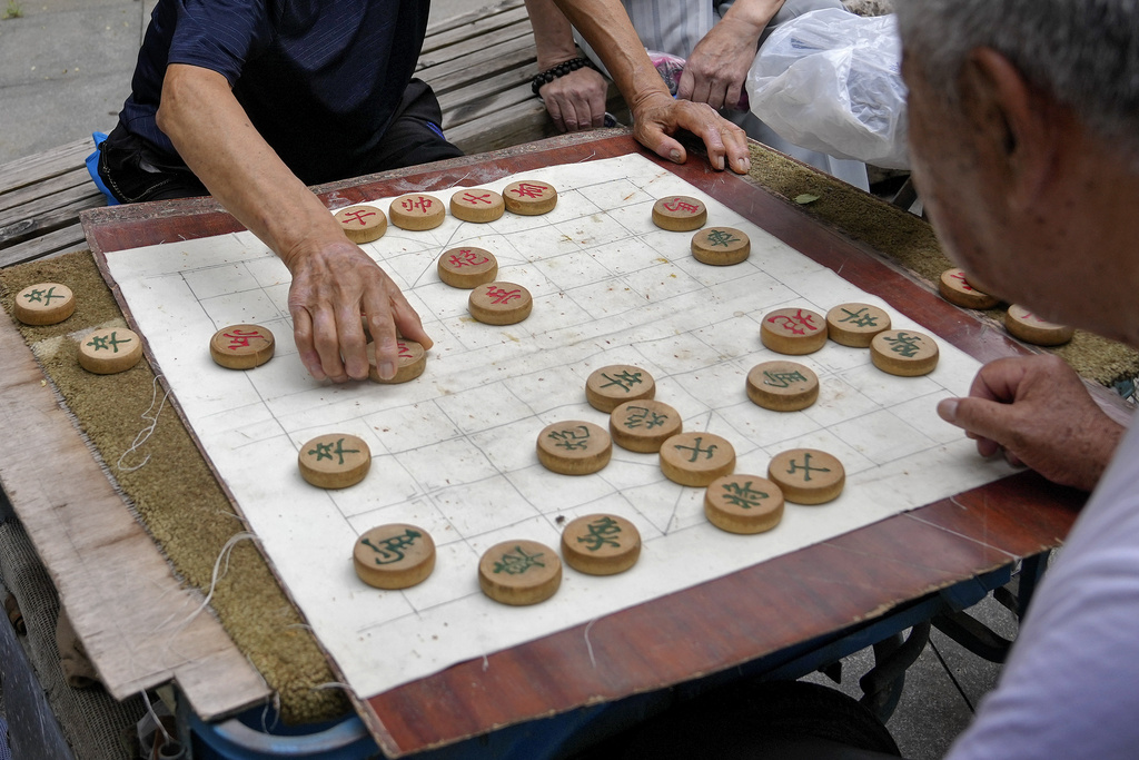 FILE - Residents play Chinese chess games outside a residential area in Beijing on July 19, 2021. 