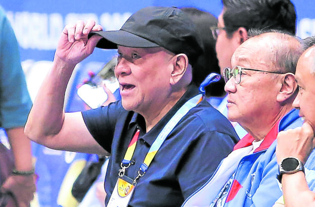 Ramon S. Ang (tipping cap) and Manny V. Pangilinan watch a Gilas Pilipinas game during the World Cup. —AUGUST DELA CRUZ