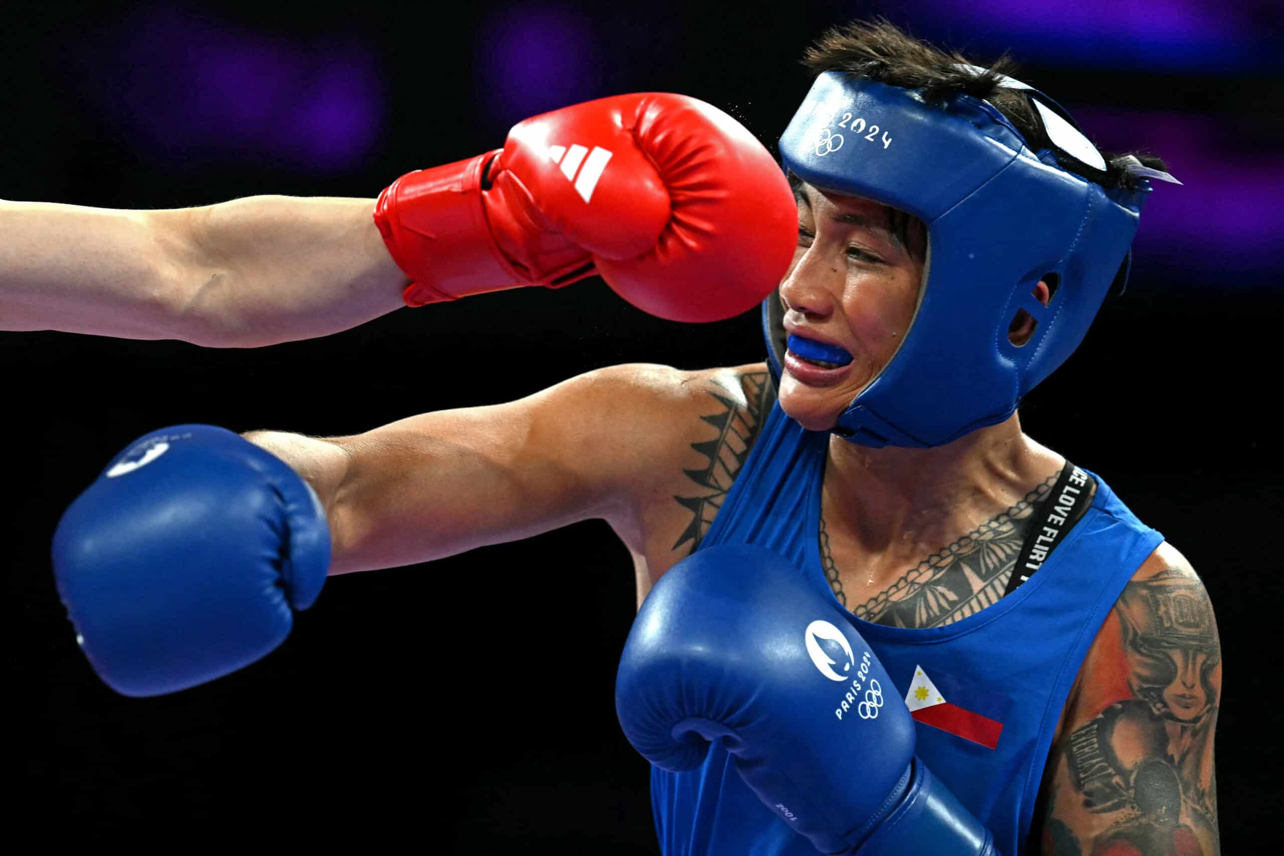 Philippines' Hergie Bacyadan (in blue) takes a punch from China's Li Qian in the women's 75kg preliminaries round of 16 boxing match during the Paris 2024 Olympic Games at the North Paris Arena, in Villepinte on July 31, 2024. (Photo by MOHD RASFAN / AFP)