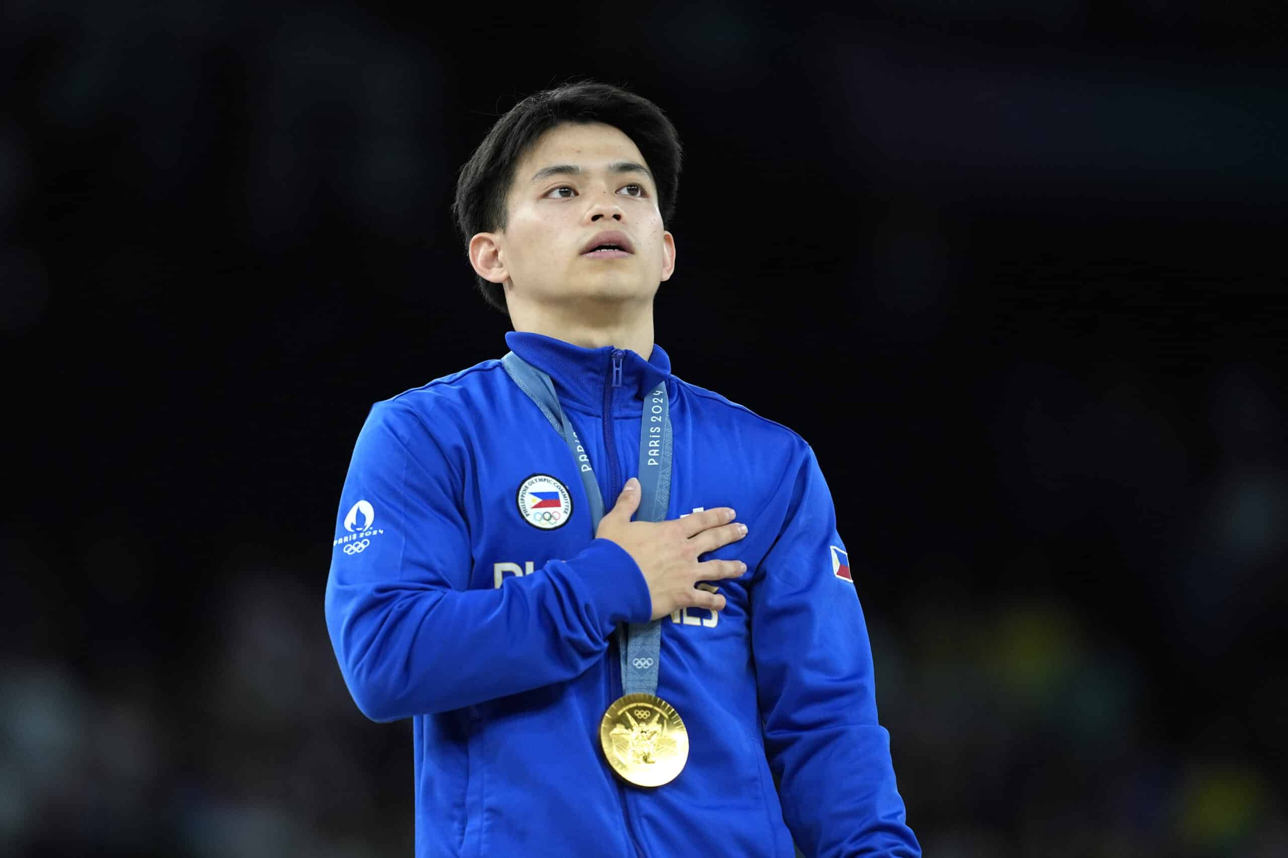 Carlos Edriel Yulo, de Filipinas, hace una pausa para el himno nacional de Filipinas mientras está de pie en el podio después de ganar la medalla de oro durante la final individual de suelo de gimnasia artística masculina en el Bercy Arena en los Juegos Olímpicos de Verano de 2024, el sábado 3 de agosto de 2024, en París, Francia. (Foto AP/Francisco Seco)