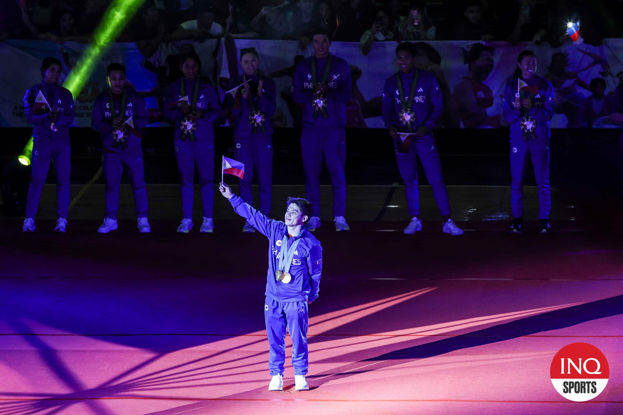 Carlos Yulo waves the Philippine flag as he faces the crowd at Rizal Memorial Colisuem, the last stop of the Heroes parade for the Filipino athletes from the Paris Olympics 2024.