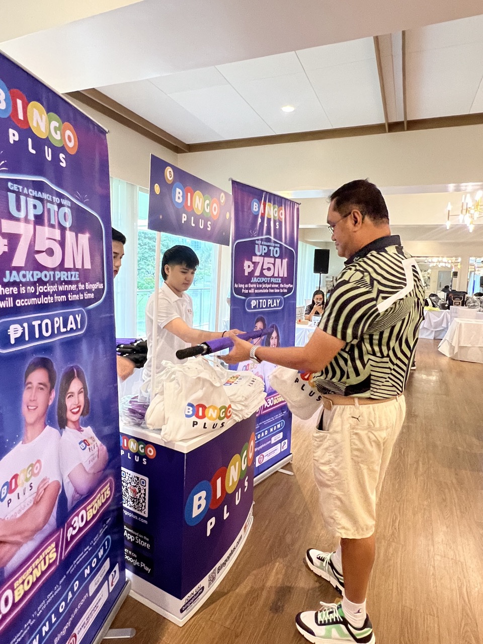 Shot of an event-goer being given free BingoPlus merchandise, including a golf umbrella.