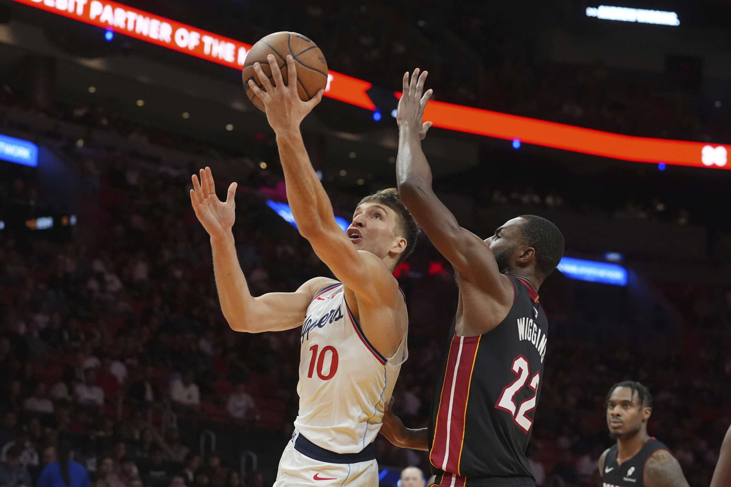 El guardia de los Clippers Bogdan Bogdanovic (10) conduce a la canasta cuando el delantero de Miami Heat Andrew Wiggins (22) defiende durante la segunda mitad de un partido de baloncesto de la NBA, el miércoles 12 de marzo de 2025, en Miami.