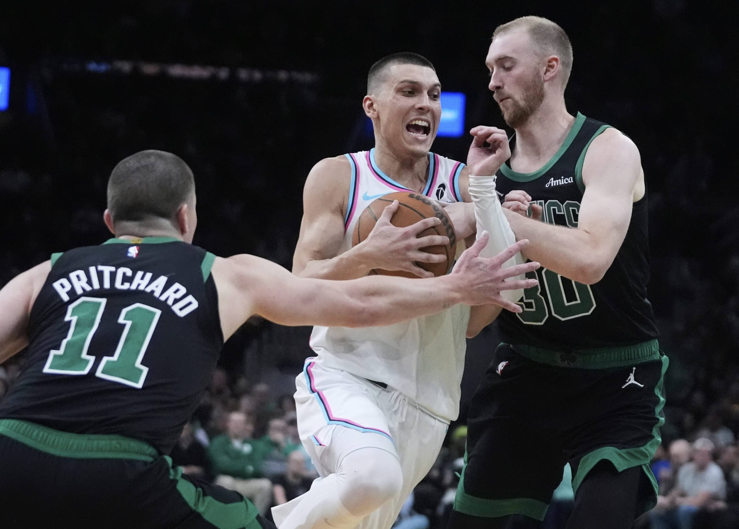 El guardia de Miami Heat, Tyler Herro, centro, conduce a la canasta entre el delantero de los Boston Celtics, Sam Hauser, a la derecha, y al guardia Payton Pritchard (11) durante la segunda mitad de un partido de baloncesto de la NBA, el miércoles 2 de abril de 2025, en Boston, en Boston