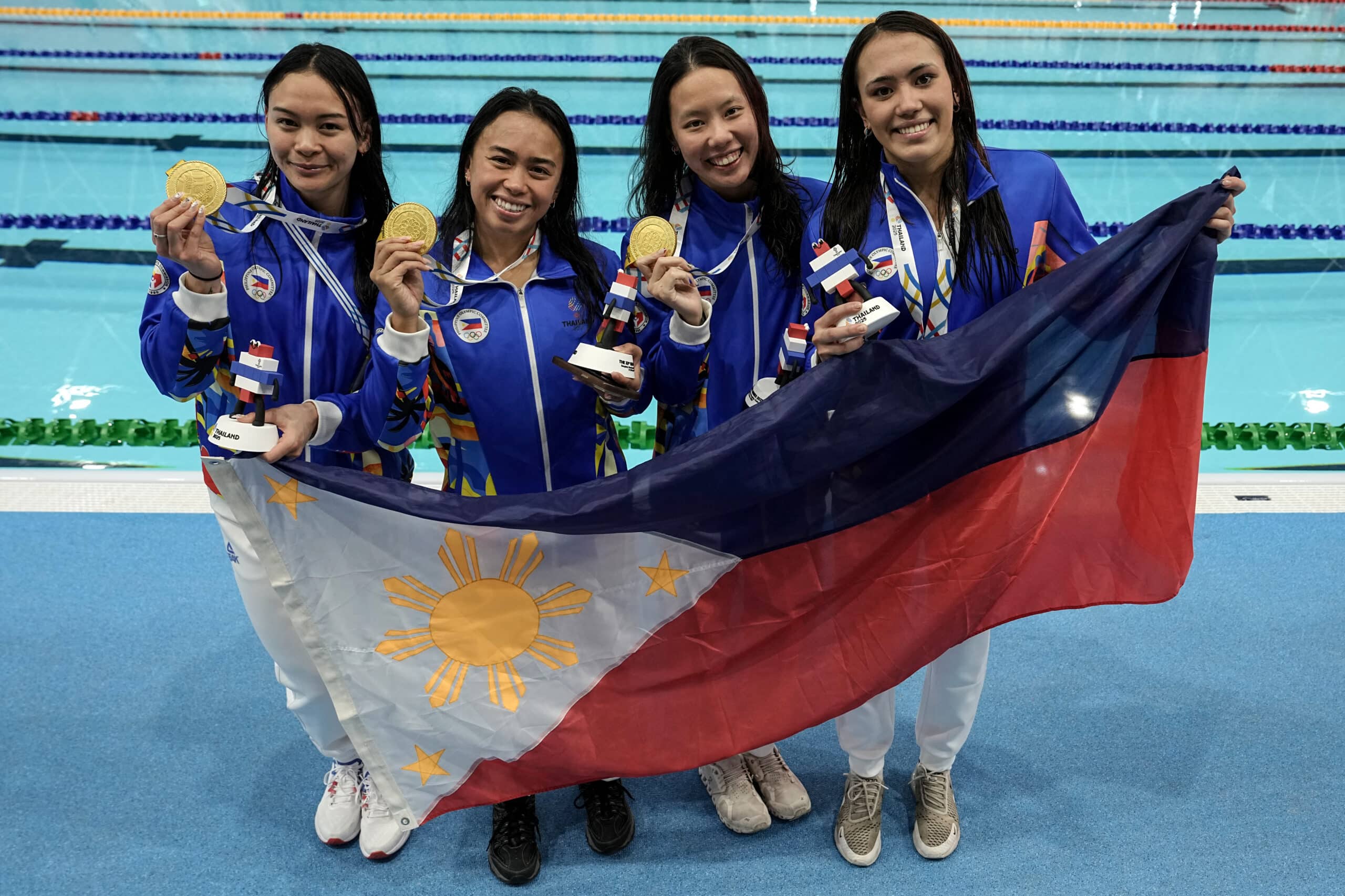 The Philippines' women's freestyle relay team celebrate with their gold medals after winning the women's 4x100m freestyle final during the swimming event of the 33rd Southeast Asian Games (SEA Games) at the Huamark Aquatic Center in Bangkok on December 10, 2025. (Photo by Chanakarn
